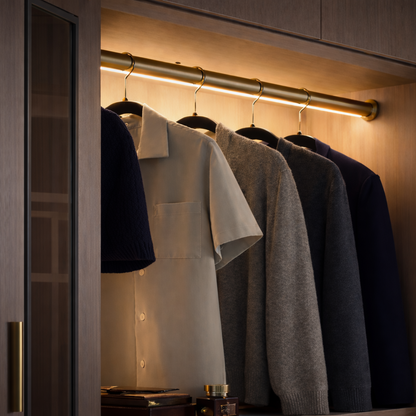 Closet with hanging clothes illuminated by a light wardrobe rail 